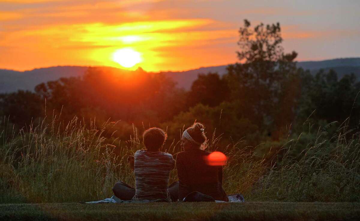 Friends Ricky Westby, of Danbury, left, and Aly Peet, of New Fairfield, watch the sunset by Lee Farms Corporate Park in Danbury in June 2016. Switching to permanent daylight-saving time would mean later sunsets in the winter, but later sunrises, too.