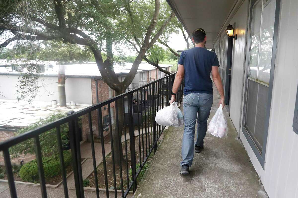 Crowdsource Rescue volunteer Ben Honey walks into an apartment complex with bags of food, for a client, from the Houston Food Bank, in Houston, Friday, April 17, 2020. During disasters, CrowdSource Resource hooks up people in trouble to volunteers who can help. "We're a bunch of tech nerds and response cowboys -- people with chainsaws and boats," says Matthew Marchetti, one of the guys who accidentally started the group during Hurricane Harvey. A pandemic wasn't their sort of crisis. Then they realized that people vulnerable to the coronavirus were going to need food, and nobody was there to deliver it.