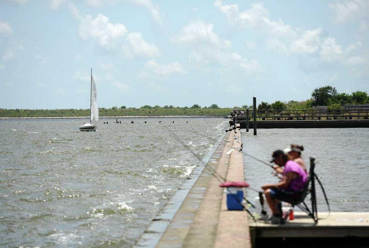 Anglers fish Sabine Lake as a sailboat heads back into the docks Saturday afternoon. Warm weather brought anglers out to the water's edge on Pleasure Island on Saturday. The Saltwater Anglers League of Texas also held a Fishing Rodeo event over the weekend. Photo taken Saturday 5/24/14 Jake Daniels/@JakeD_in_SETX