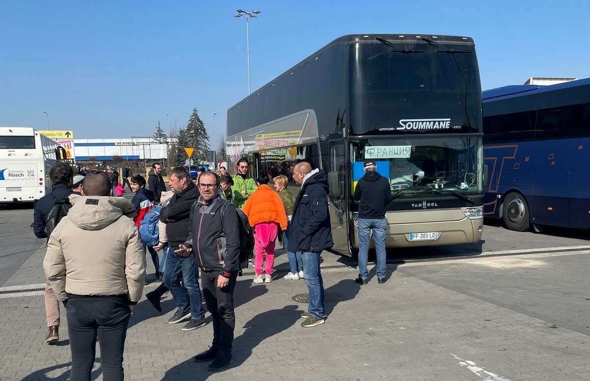 Ukrainian refugees and volunteers prepare to board a bus in Poland en route to France.