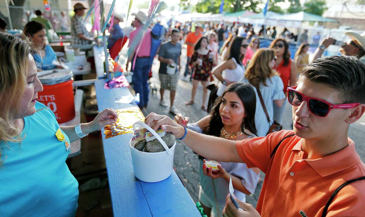 Sandra Urdialez (from left) sells some oysters to Maria Alejo, and Antoan Teodossiev during the 2017 Fiesta Oyster Bake at St. Mary’s University.