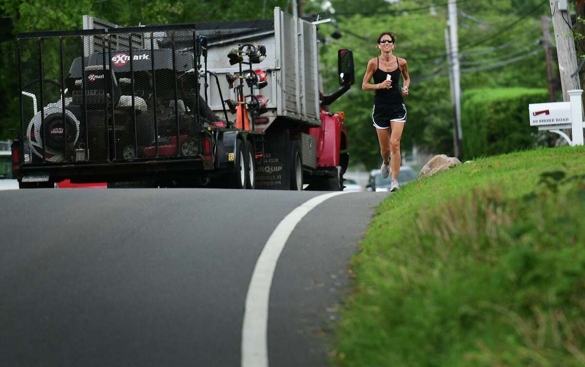 A jogger runs along Shore Road on Aug. 19, 2021, in Greenwich. Resident Maggie Bound is leading a community effort to demand that the town, as part of the budget process, approve funds for a new sidewalk along the busy road.