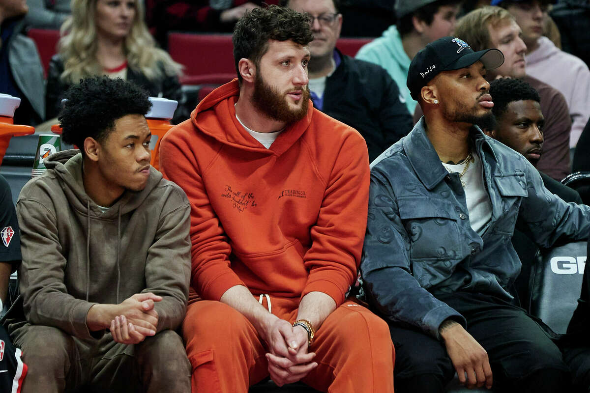 Injured Portland Trail Blazers guard Anfernee Simons, left, center Jusuf Nurkic, center, and guard Damian Lillard watch from the bench during the first half of the team's NBA basketball game against the Houston Rockets in Portland, Ore., Friday, March 25, 2022.