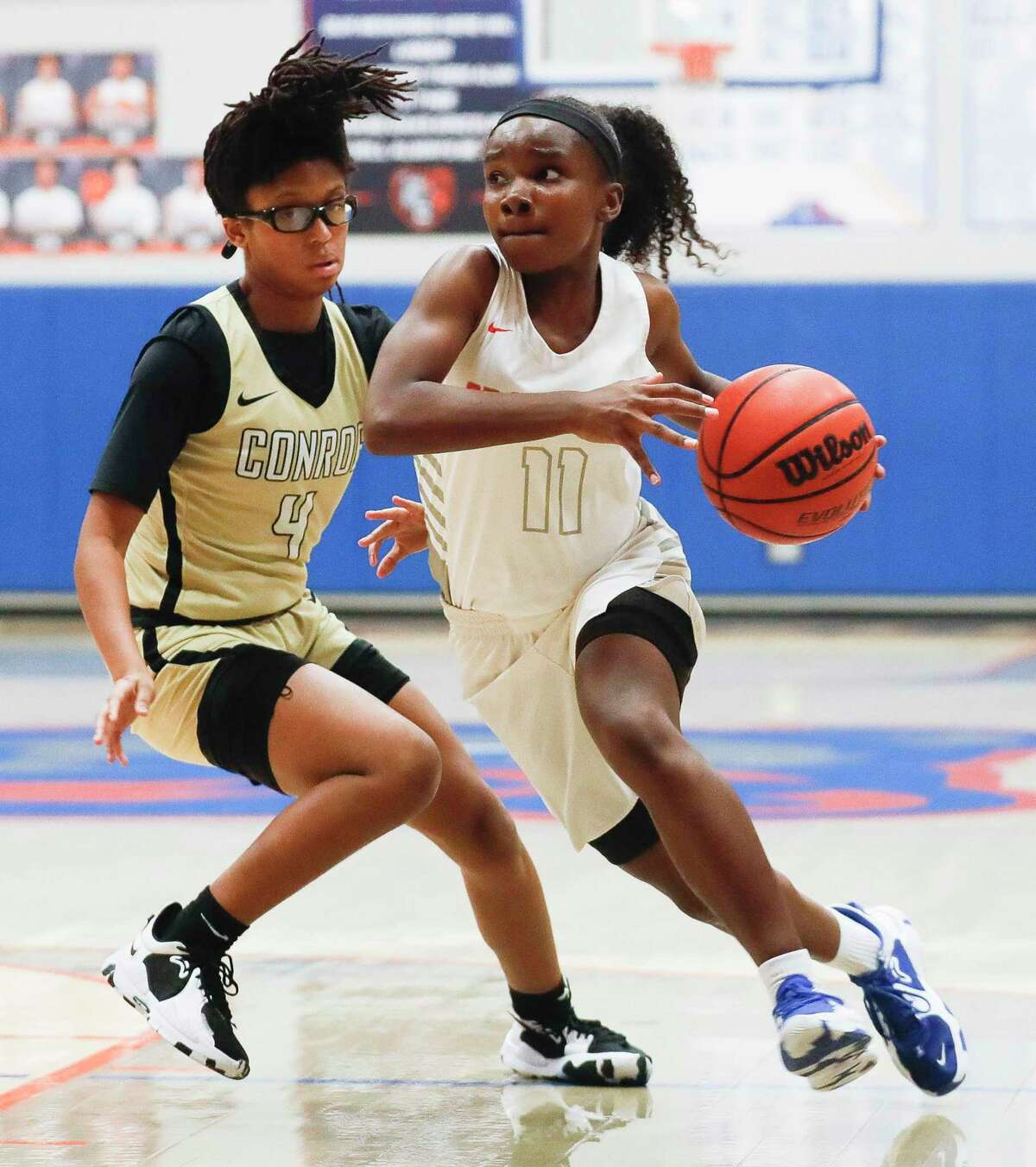 Grand Oaks' Bree Riley (11) drives past Conroe's Alana Harris (4) during the first quarter of a high school basketball game at Grand Oaks High School, Wednesday, Feb. 2, 2022.