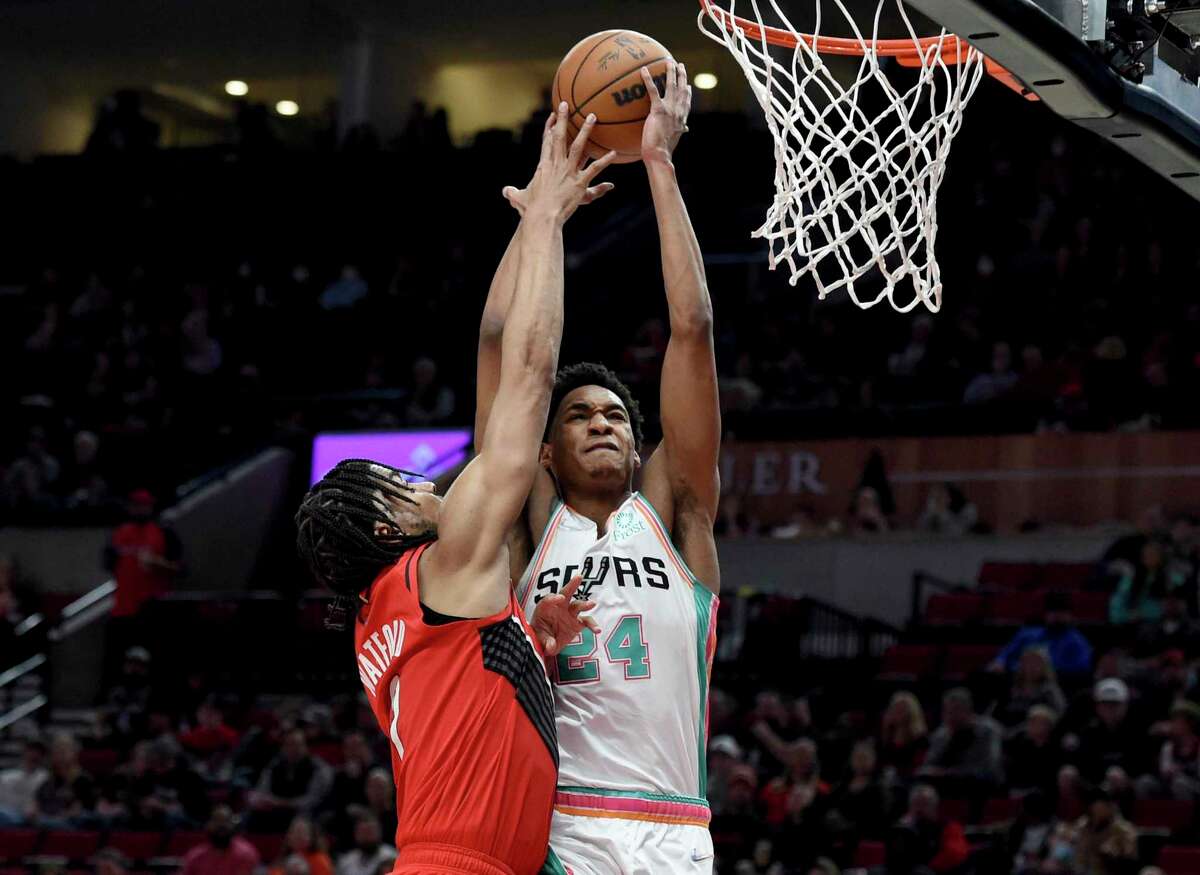 San Antonio Spurs guard Devin Vassell, right, drives to the basket on Portland Trail Blazers forward Trendon Watford during the first half of an NBA basketball game in Portland, Ore., Wednesday, March 23, 2022.