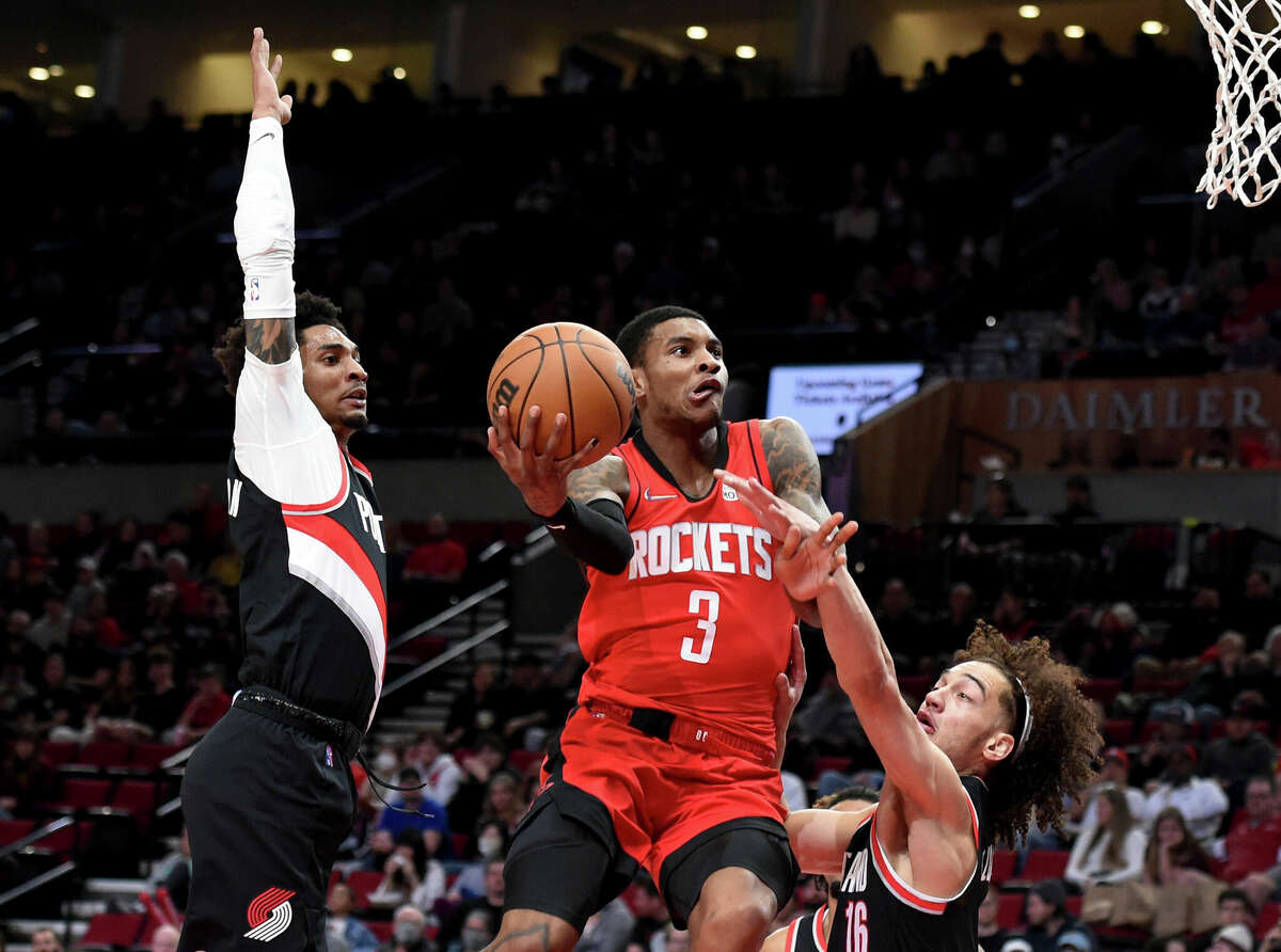 Houston Rockets guard Kevin Porter Jr., center, drives to the basket on Portland Trail Blazers guard Keon Johnson, left, and guard CJ Elleby, right, during the first half of an NBA basketball game in Portland, Ore., Saturday, March 26, 2022.(AP Photo/Steve Dykes)