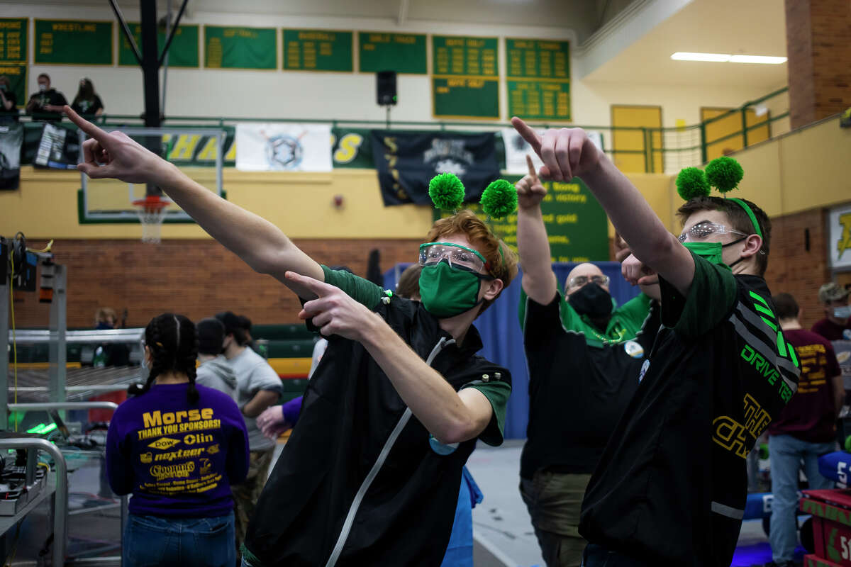 H. H. Dow High School students TJ Neuenfeldt, left, and Robert Roe, right, point to their supporters in the crowd before competing in a match during a FIRST Robotics competition Friday, March 25, 2022 at H. H. Dow High School.