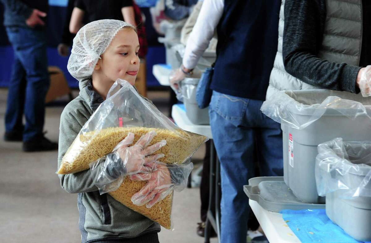 Above, C.C. Daniel, 8, carries a bag of noodles during the “Pack-A-Thon” at Christ Church Greenwich on Saturday. As many as 200 volunteers worked to reach a goal to provide 36,000-plus packages of nutritious meals for refugees on the border of Poland. The meals will be shipped to Poland in coordination with the Ukrainian Cultural Center in New Jersey.