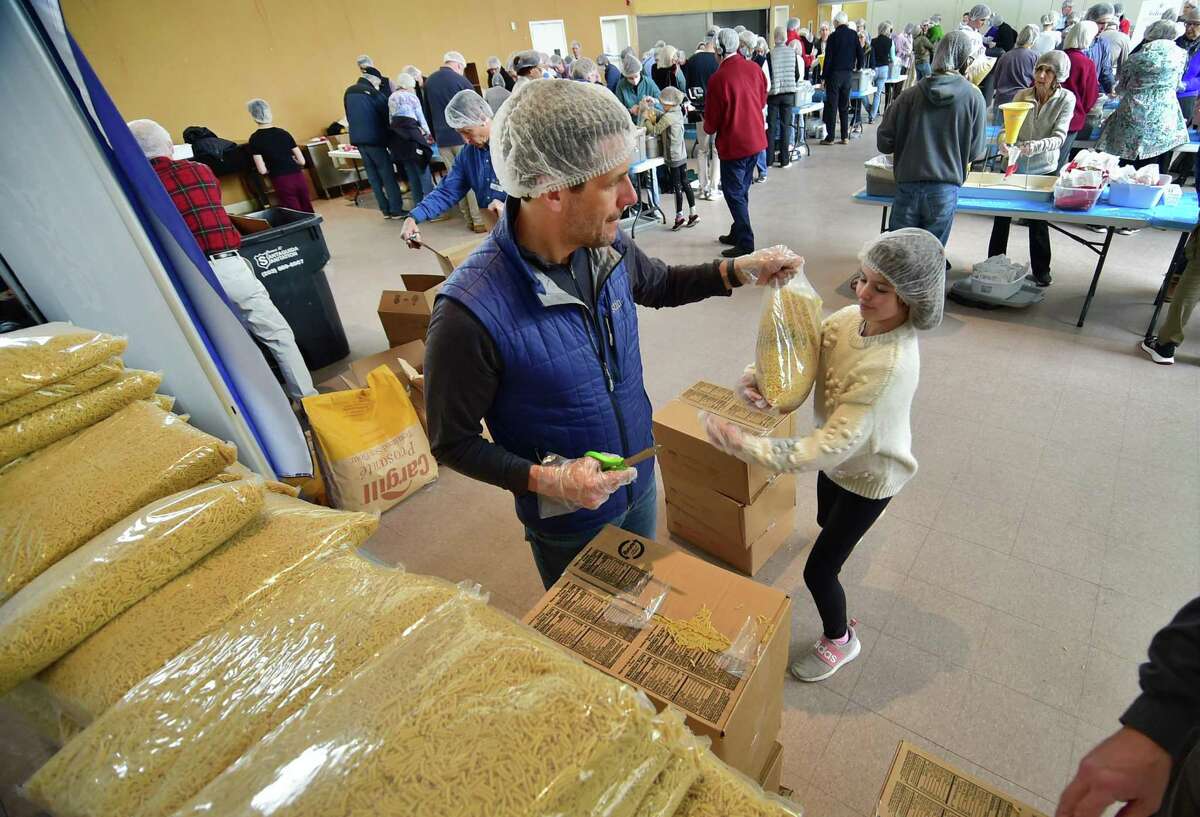 Volunteer Chris Hentemann hands out bags of noodles to refill workers bins during an emergency "Pack-A-Thon" event at Christ Church Greenwich in Greenwich, Conn., on Saturday March 26, 2022. As many as 200 volunteers worked to reach the goal of providing 36,000-plus packages of nutritious meals for refugees on the border of Poland. The meals will be shipped to Poland in coordination with the Ukrainian Cultural Center in New Jersey.