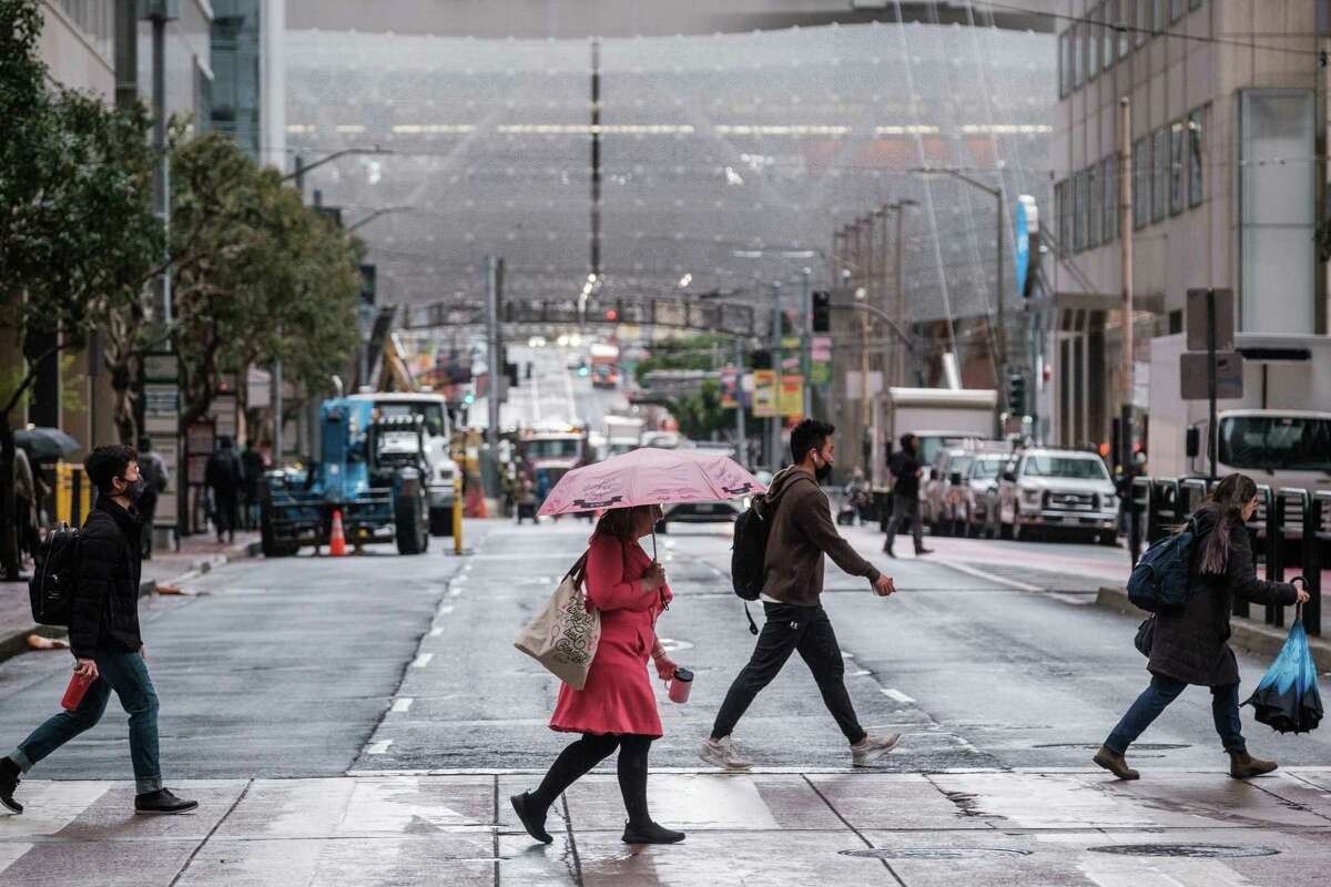 A pedestrian walks with an umbrella during a light rain in downtown San Francisco on Monday, March 28, 2022. Rain fell around the Bay Area overnight bringing some relief from record hot and dry weather as rainy season heads toward a conclusion.