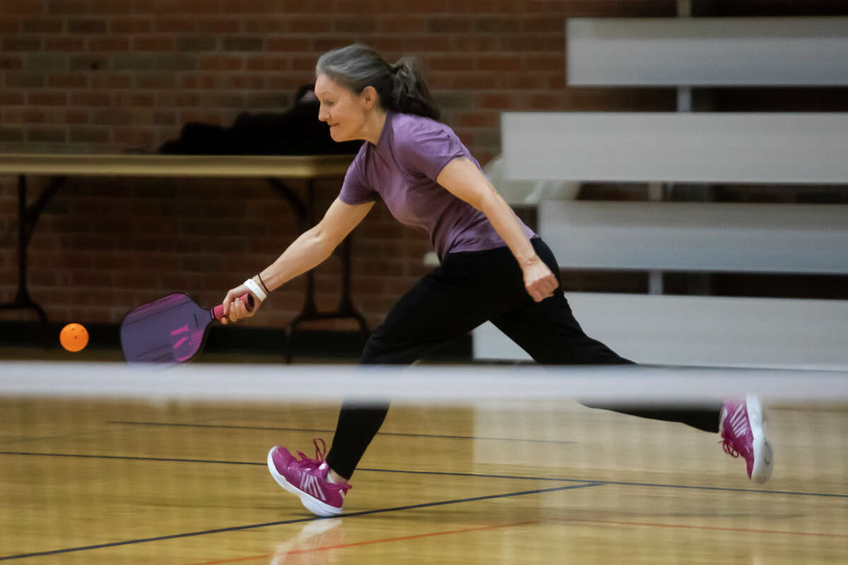 Maureen "Mo" Acker lunges foreward to return the ball while playing in a pickleball match Wednesday, March 23, 2022 at the Greater Midland Community Center.