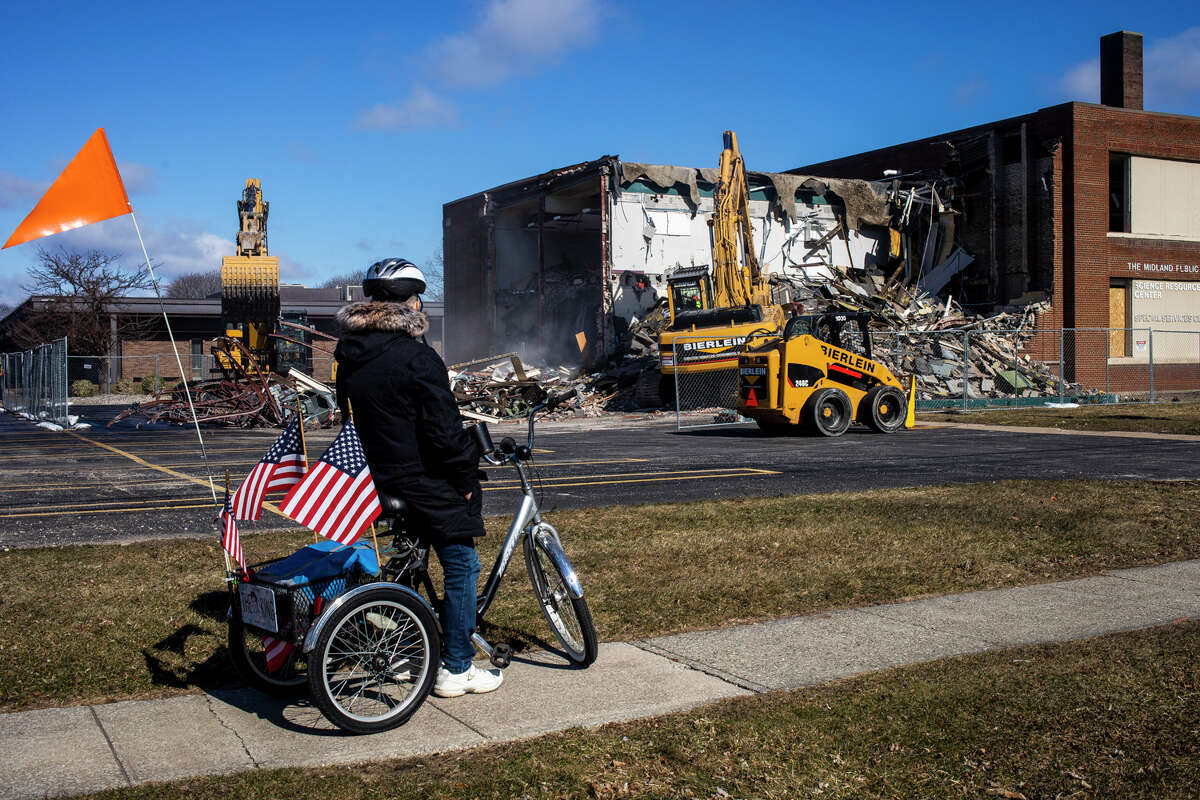 Brad Johnson of Midland stops on his bicycle to watch as the building at 815 State Street in Midland, formerly the State Street School, is demolished Monday, March 28, 2022.