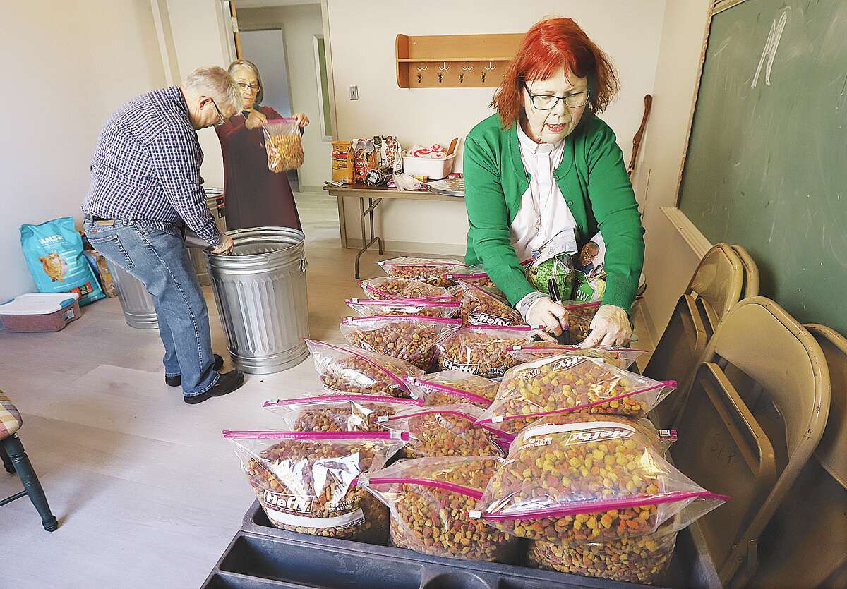 John Badman|The Telegraph The Rev. Cynthia Sever, right, labels bags of dog food being prepared for the distribution from what is believed to be the area's first pet food pantry, the 4 Paws Pet Food Pantry at St. Paul's Episcopal Church in Alton. Volunteers like her husband, Byron Sever, and Mimi Almonroeder, background, worked Sunday in preparation for the pantry's opening day set for May 1.
