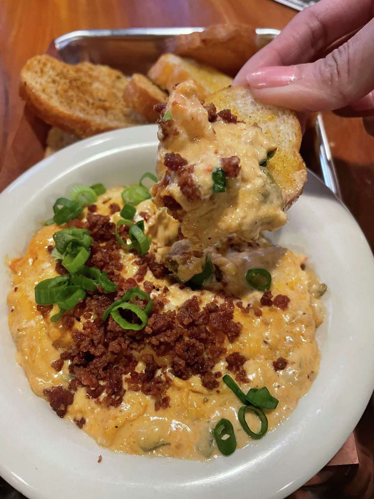 The Blood Bros. BBQ features a seasoned seafood dip: a creamy blend of cheese with shrimp, chunk crab and crayfish, topped with a hot link crumble and green onions.