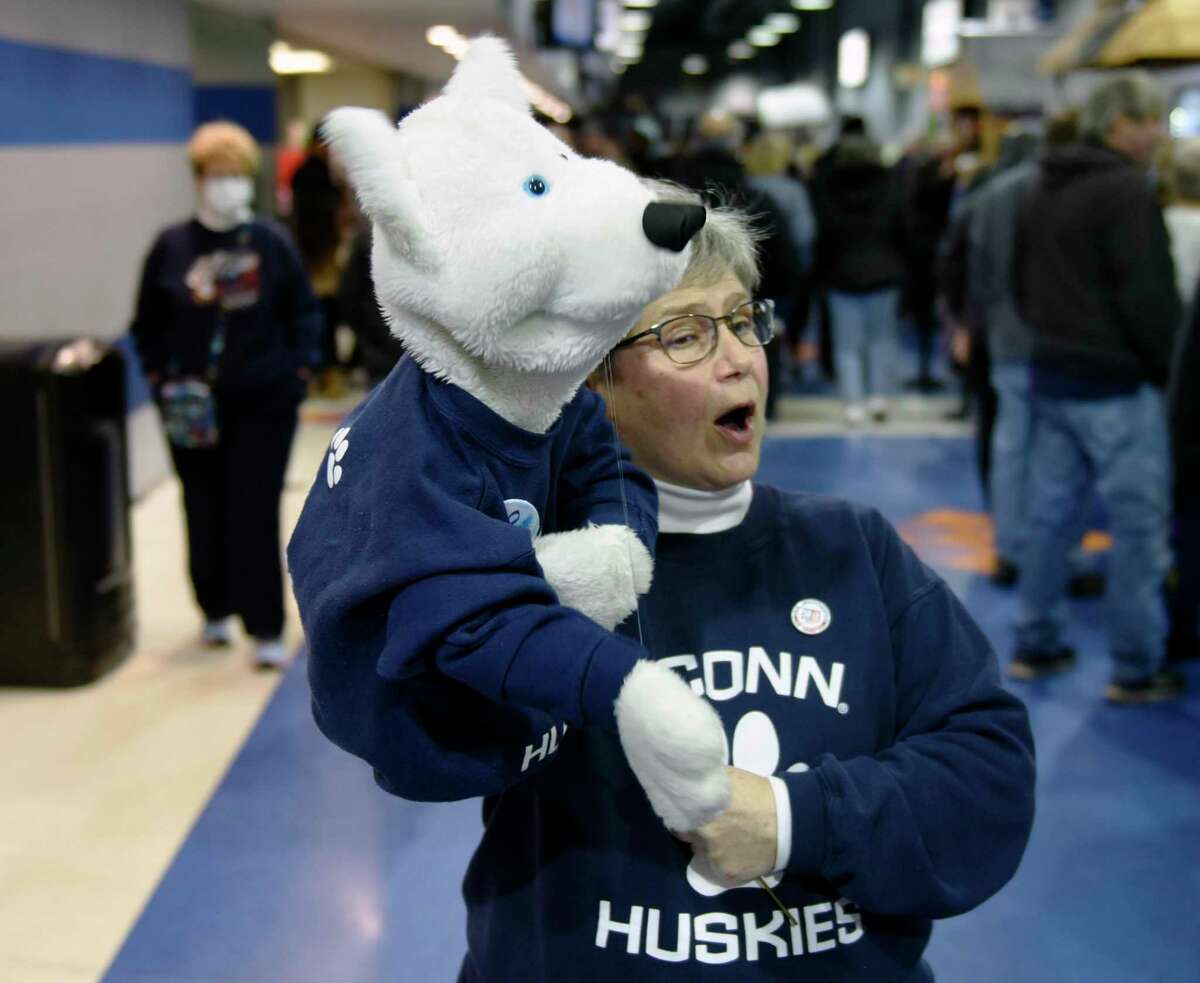 Simsbury resident Carol McKenzie and her husky mascot, J.J., cheer for UConn at Total Mortgage Arena in Bridgeport on Monday.