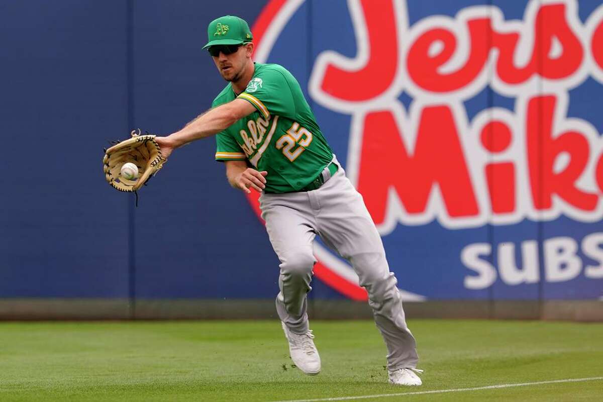 Oakland Athletics' Stephen Piscotty (25) fields a base hit by Los Angeles Angels' Matt Duffy during the third inning of a spring training baseball game, Monday, March 28, 2022, in Tempe, Ariz. (AP Photo/Matt York)