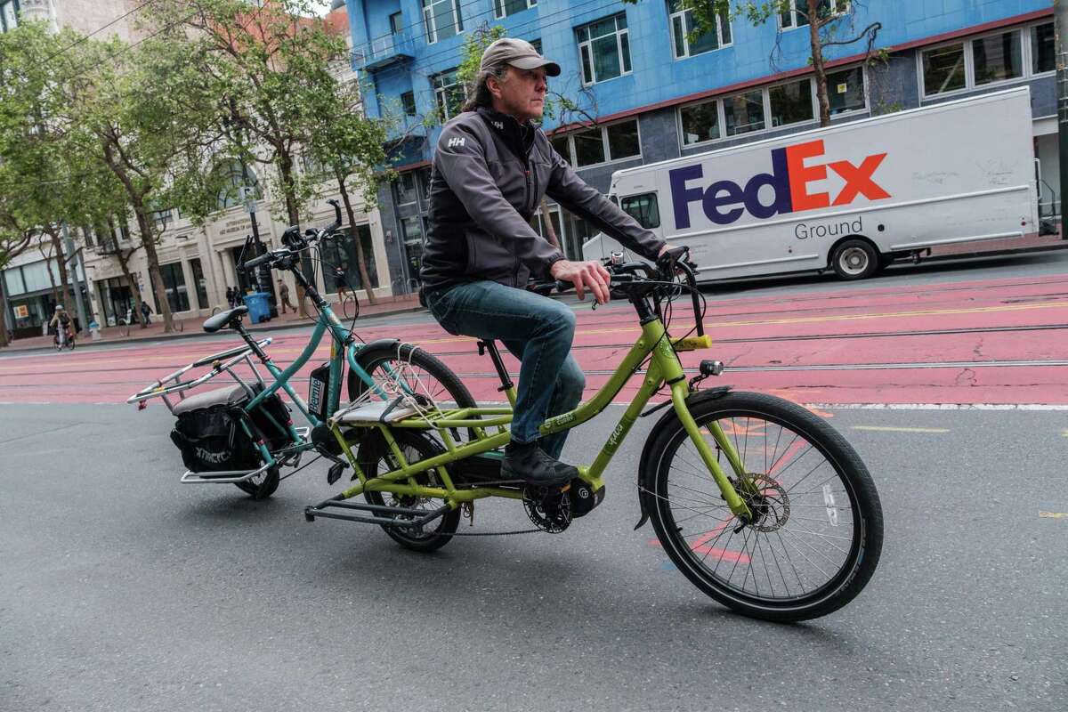 Kash transports a customer’s bike back to his shop on Market Street for repairs.