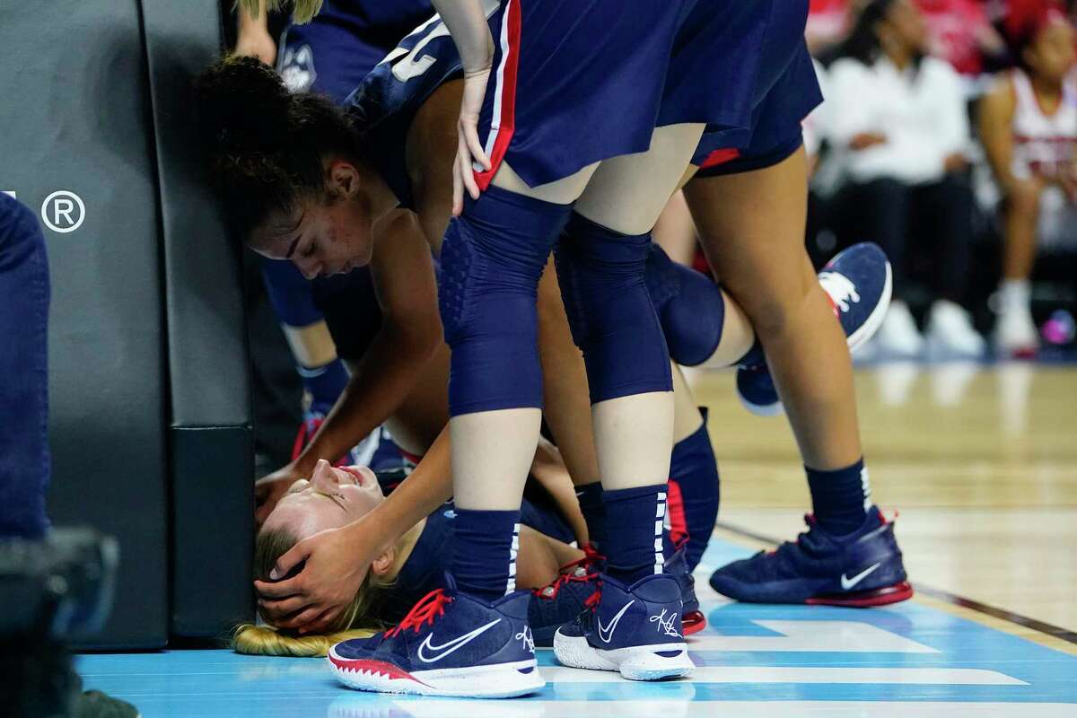 UConn guard Evina Westbrook (22) checks on forward Dorka Juhász after Juhász was injured on a play during the second quarter against NC State in the East Regional final college basketball game of the Women’s NCAA Tournament, Monday, March 28, 2022, in Bridgeport, Conn.