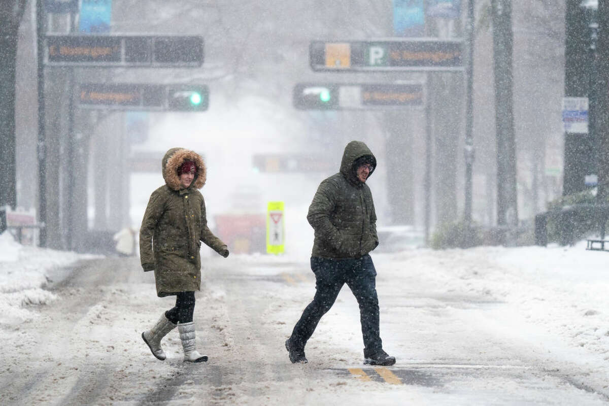Pedestrians cross a street in the snow on Jan. 16, 2022 in Greenville, South Carolina. (Photo by Sean Rayford/Getty Images)