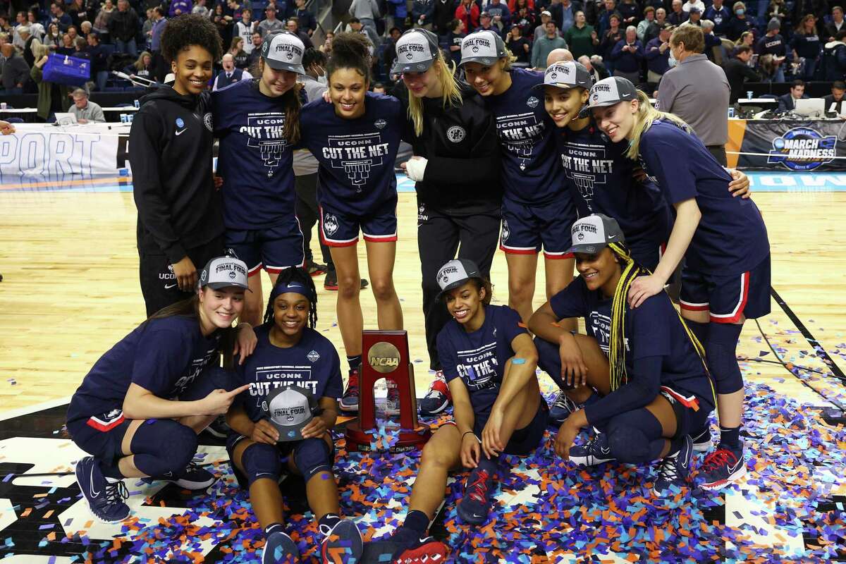 BRIDGEPORT, CONNECTICUT - MARCH 28: Members of the UConn Huskies pose for photos with the regional championship trophy after defeating the NC State Wolfpack 91-87 in 2 OT in the NCAA Women's Basketball Tournament Elite 8 Round at Total Mortgage Arena on March 28, 2022 in Bridgeport, Connecticut. (Photo by Elsa/Getty Images)