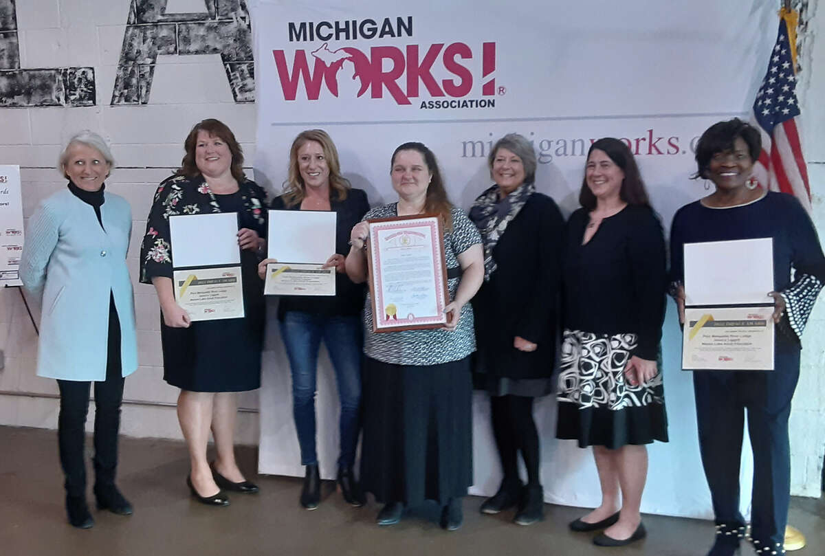 Jessica Liggett (center) receiving the Impact Award during a ceremony March 25 in Lansing.
