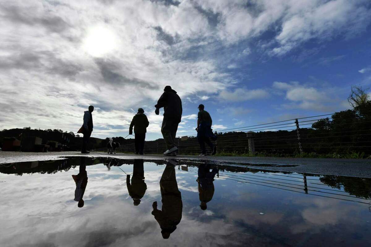 A large puddle reflects a cloudy sky as walkers enjoy an early morning walk around the Lafayette Reservoir in Lafayette, Calif., on Monday, March 28, 2022. The Bay Area experienced some much needed rain Sunday and Monday. (Jose Carlos Fajardo/Bay Area News Group via AP)
