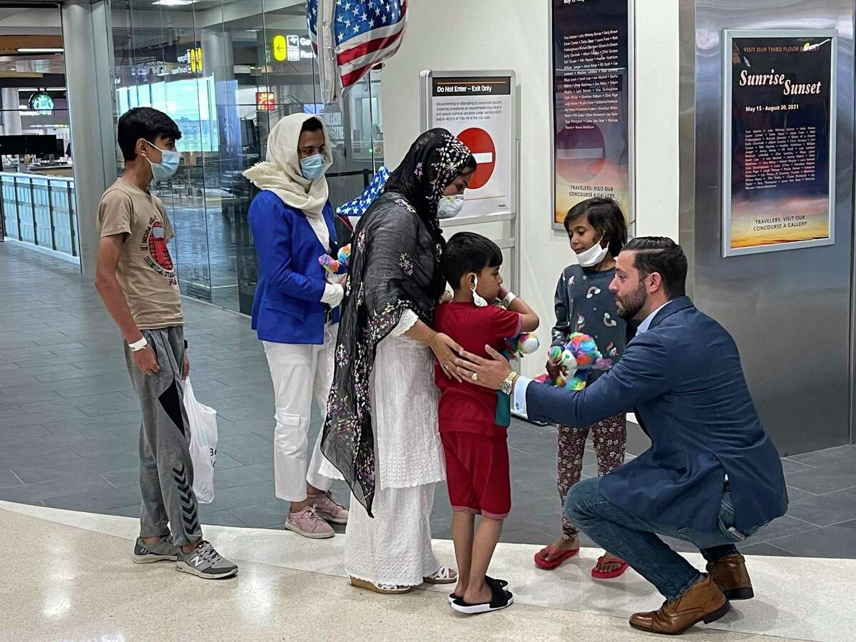 Alex Plitsas, a U.S. Army veteran who helped shepherd Afghan refugees through the evacuation process, greets Suneeta and her four children at Albany International Airport on Aug. 30, 2021.