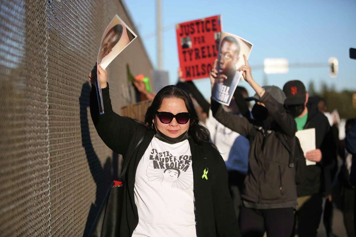 Jennifer Leong carries a photo of Tyrell Wilson as she marches over a Highway 680 overpass in Oakland, last month. Wilson was fatally shot last year by the same Contra Costa County sheriff’s deputy who killed Leong’s brother Laudemer Arboleda in 2018. Leong is calling for the resignation of Sheriff David Livingston, who defended the deputy even after he was sentenced to six years in state prison in connection with the Arboleda shooting.