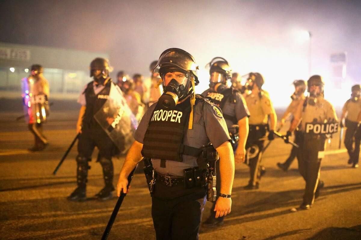 Police advance through a cloud of tear gas toward demonstrators protesting the killing of teenager Michael Brown on August 17, 2014 in Ferguson, Missouri.