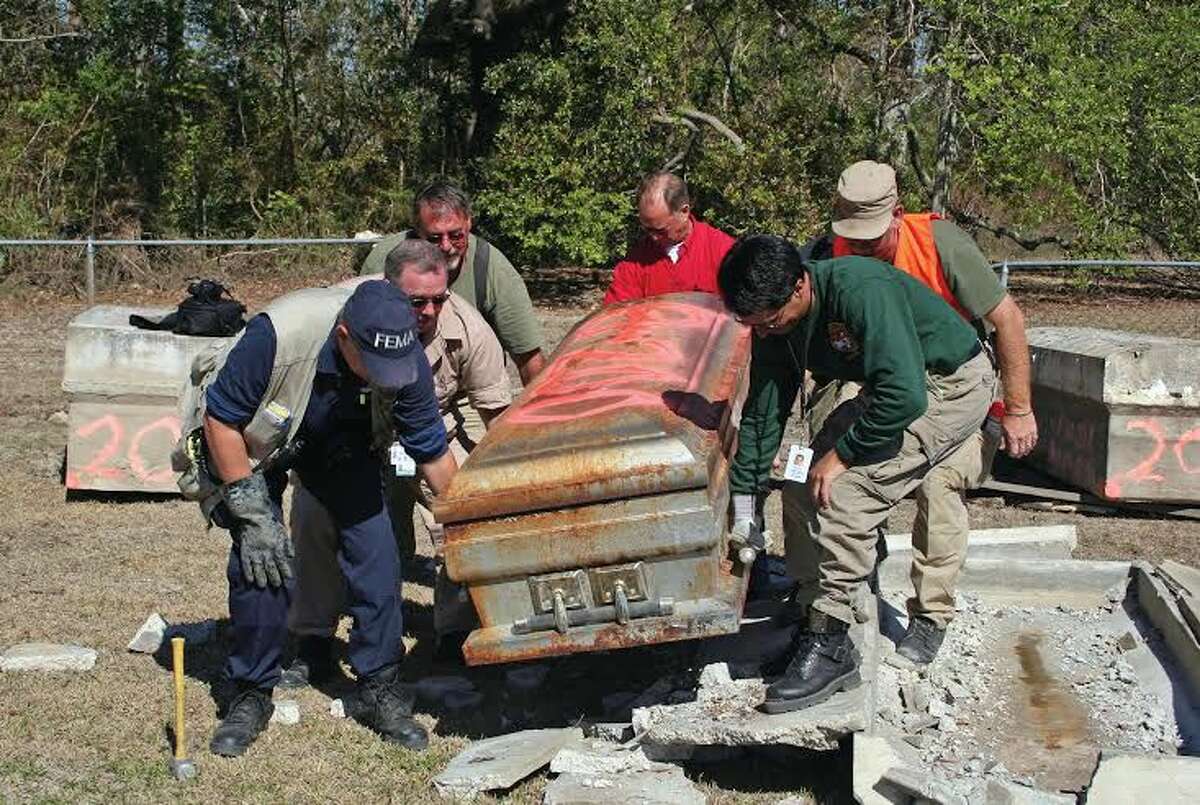 Members of DMORT remove a casket from its crypt so it can be re-interred after the enormous storm surge from Hurricane Rita pushed many crypts in Louisiana hundreds of yards from previously shallow graves.
