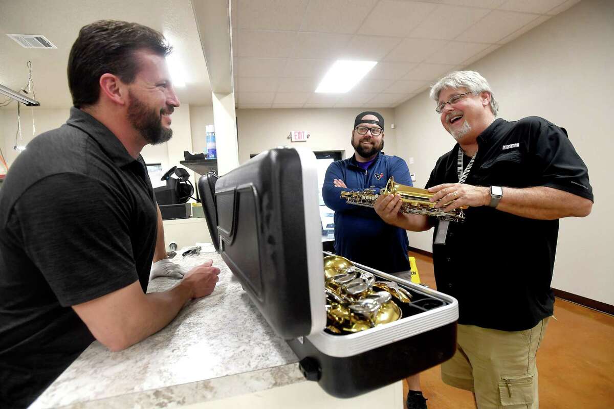 Owner Kurt Killion (right) jokes with Steve Huelsman (left) Todd Culver as they look over some recently returned rental instruments at Swicegood Music Company's new location on Twin City Highway in Nederland. Photo made Tuesday, March 22, 2022 Kim Brent/The Enterprise