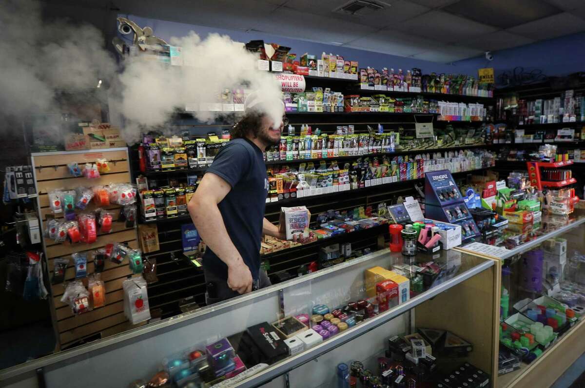 Ron Obert exhales a cloud as he works Tuesday, March 29, 2022, at Eado Glass and Smoke in Houston. Houston City Council on Wednesday will consider a proposal to ban e-cigarettes and vaping in public spaces, under the city’s smoking ordinance. “If it’s all really about health, just let people keep doing the healthier option,” he said comparing vaping and smoking.