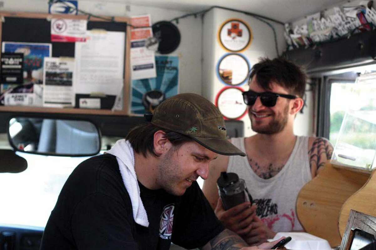 Jitter Bus co-owner Paul Crosby, left, in his “office” with a friend.