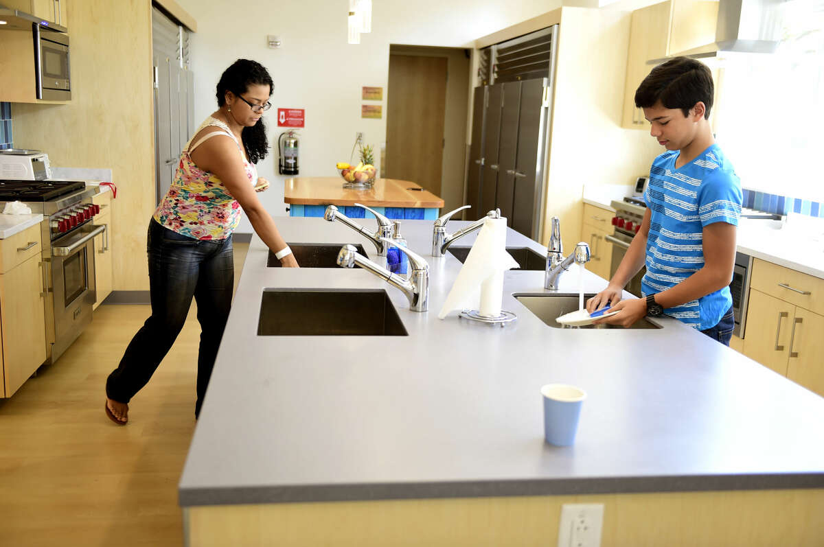 New Haven, Connecticut: July 19, 2017. Denys Sanchez of Bridgeport, whose daughter is hospitalized at the Yale New Haven Childrens hospital, left, and Gianfranco Candido, 14, of Venezuela, whose older brother is being treated at the hospital, clean their dishes in the communal kitchen at the new Ronald McDonald House on Howard Ave. in New Haven across from the YNH Childrens Hospital.