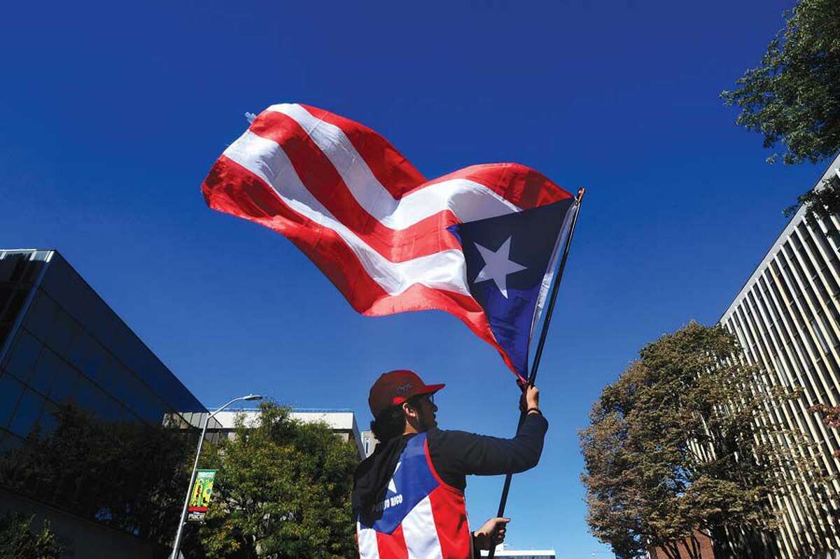 Onyx Velez, of Stamford, waves the Puerto Rican flag on Summer Street for a collection drive for Puerto Rico in downtown Stamford in October.