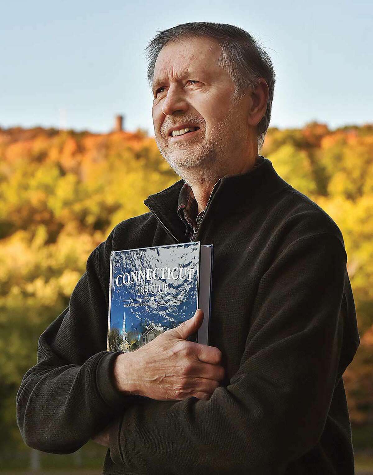 East Hampton resident Martin Podskoch, author of Connecticut 169 Club: Your Passport & Guide to Exploring Connecticut, at Hubbard Park in Meriden, with Castle Craig on the treeline in the background.
