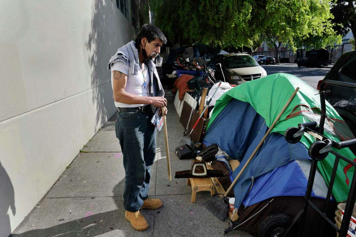 Jose Vera arranges items at his encampment along Folsom Street in the Mission District.