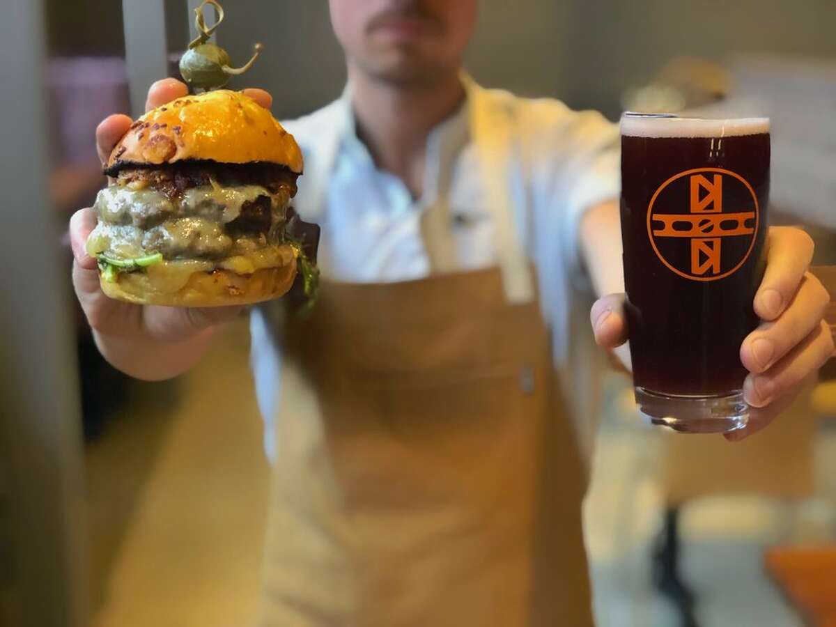 A server at Nolo carries a burger and a beer to a customer.