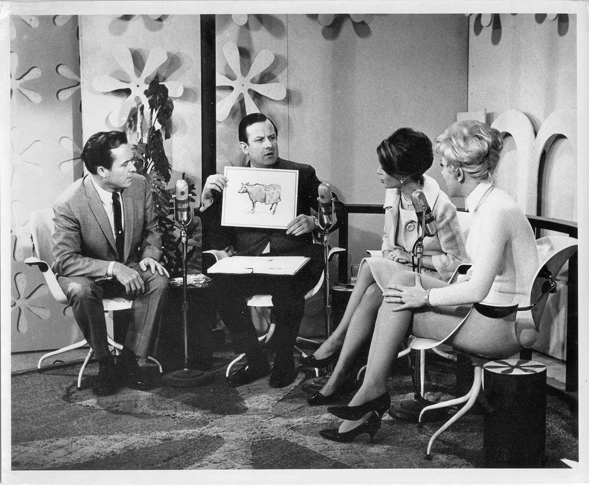 Alan Abel holding an illustration of a cow wearing a muumuu on "The Mike Douglas Show" (early 1960s)