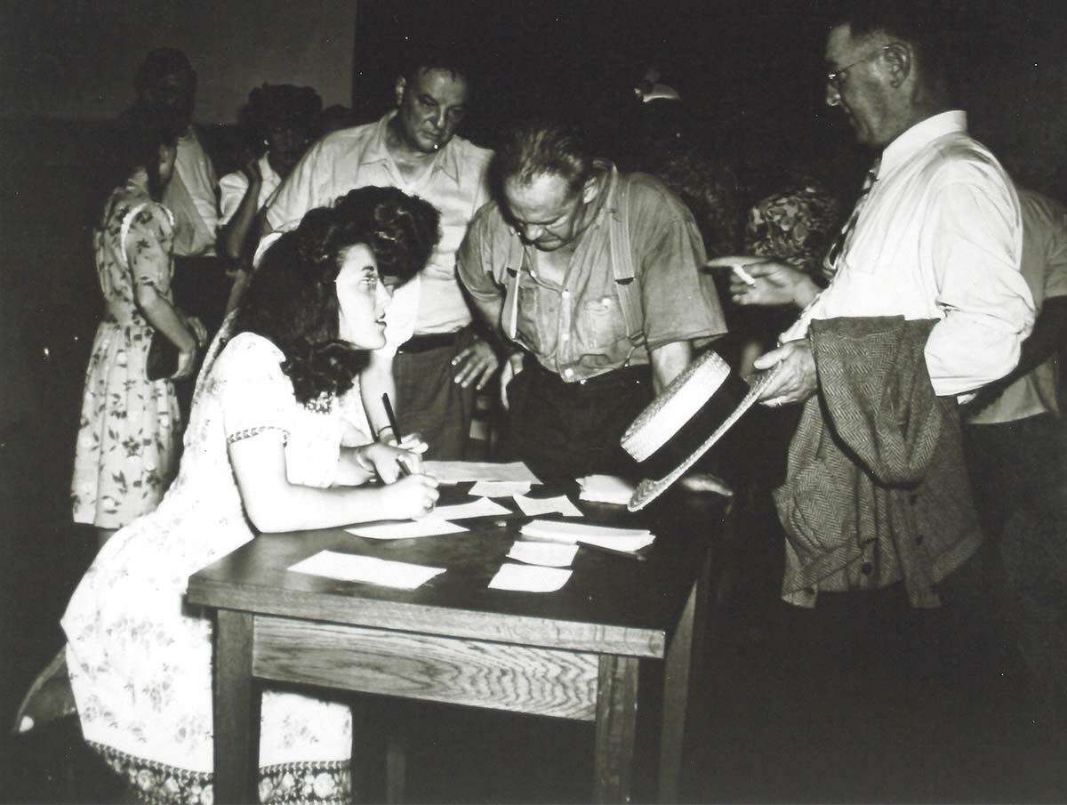 The information desk at the State Armory building in Hartford, where a temporary morgue was assembled for the identification of those who perished in the circus fire. These men rushed to the armory from work looking for their wives and children.