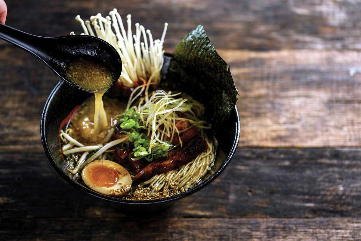 Embrace The Darkness: Tiger Belly Noodle Bar’s signature dish is a savory pork-bone broth served with slow-cooked pork belly, a pickled egg, sesame seeds, veggies and noodles.