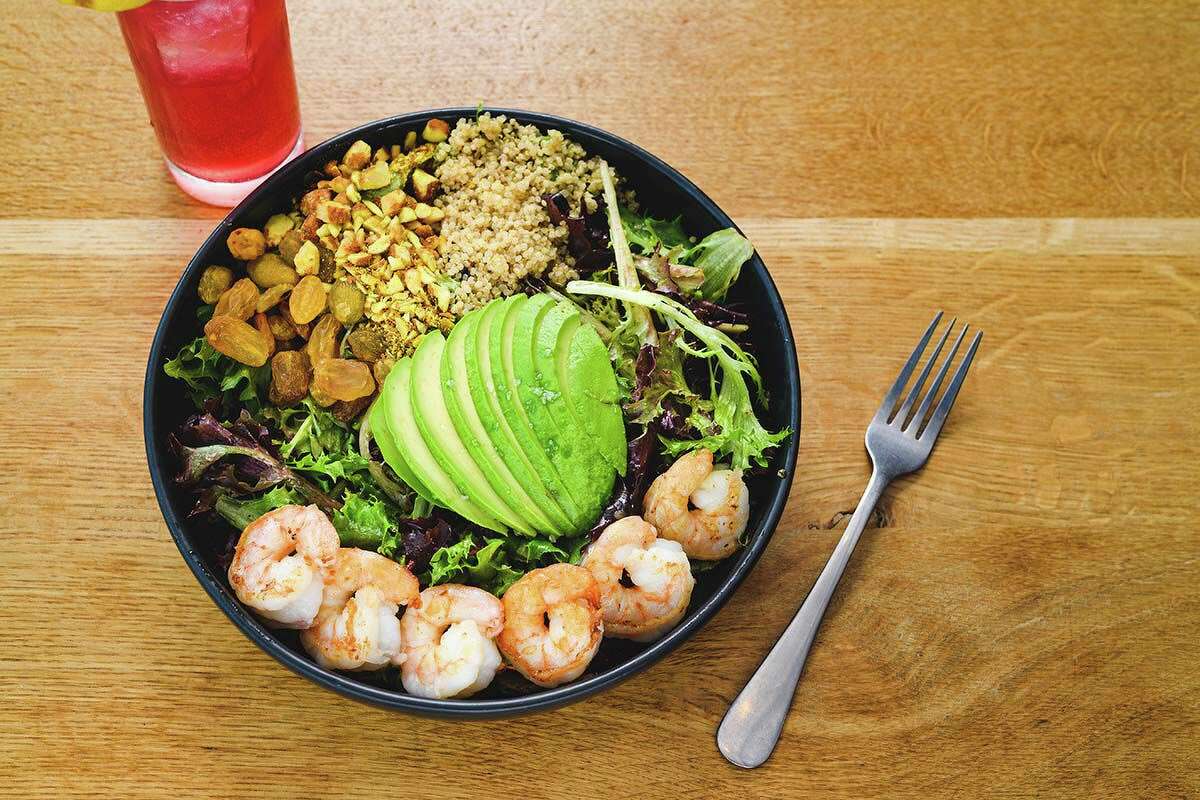 The roasted shrimp salad is made with market greens, quinoa, avocado, spiced almond, golden raisins and white balsamic vinaigrette.