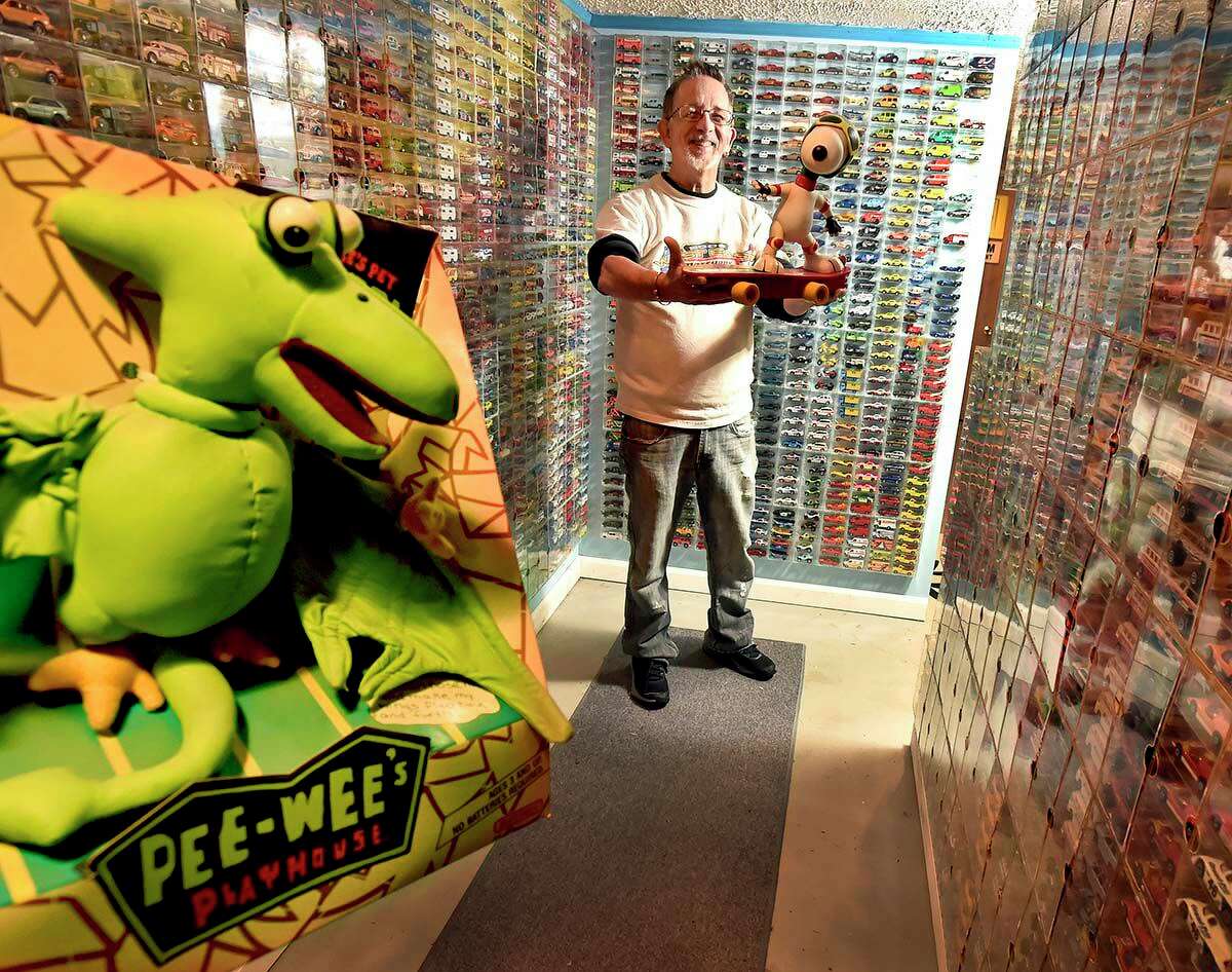 Charlie Mack stands among a small portion of his of Matchbox toys collection and holds a late circa 1980s Snoopy Skateboard R/C radio controlled toy, also manufactured by Matchbox. In the foreground is a circa 1988 Pee-Wee's Playhouse-branded Pet Pteri Matchbox toy.