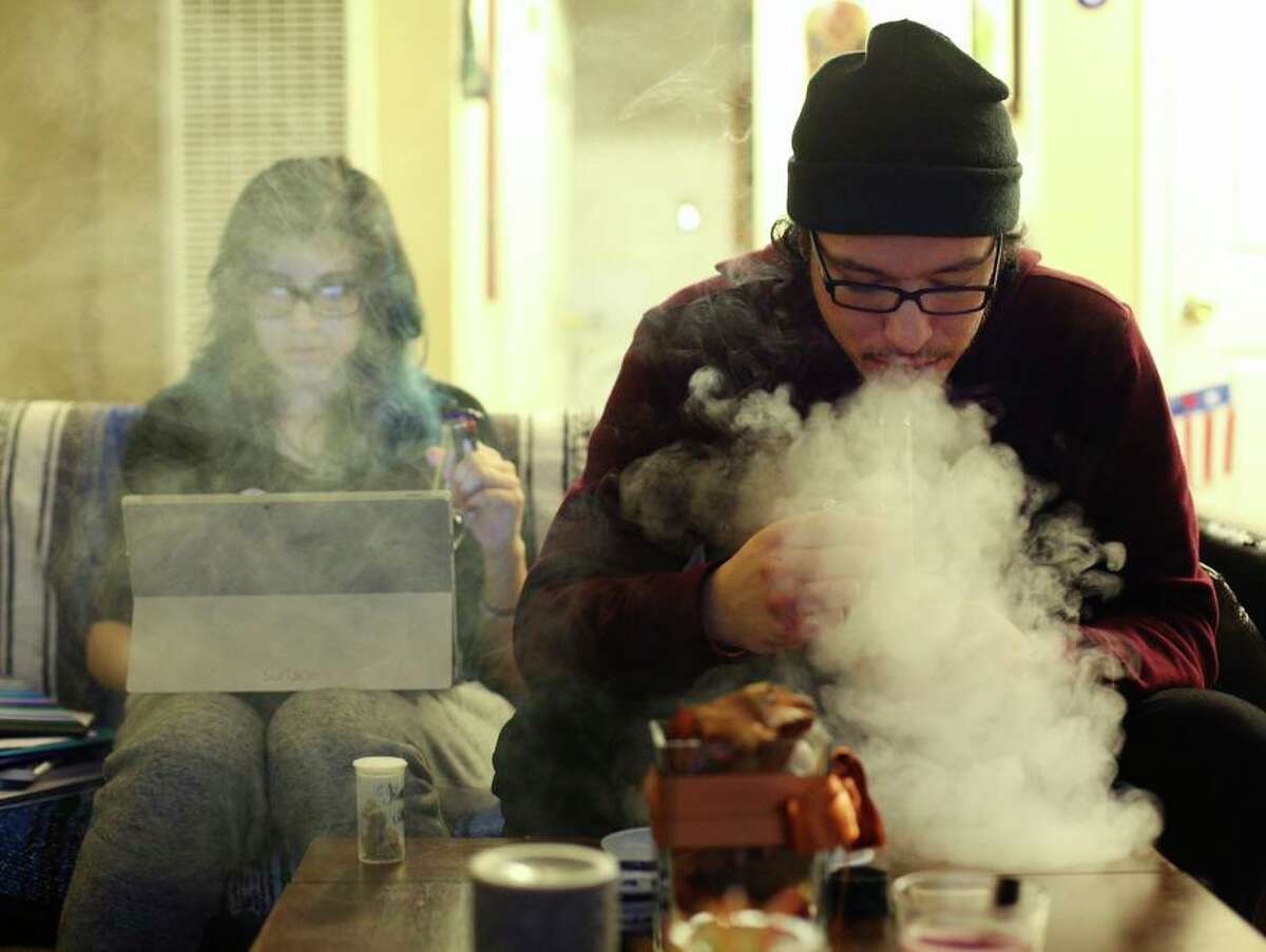 Chris (right) exhales after taking a hit from a bong, as his girlfriend Iris works on homework