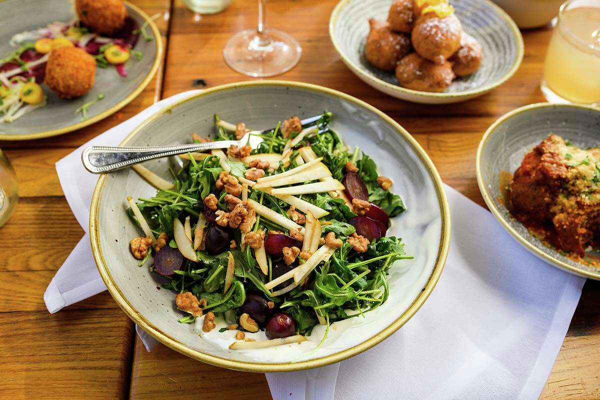 The pear and arugula salad also includes whipped Taleggio cheese, spiced walnuts, and balsamic roasted grapes.