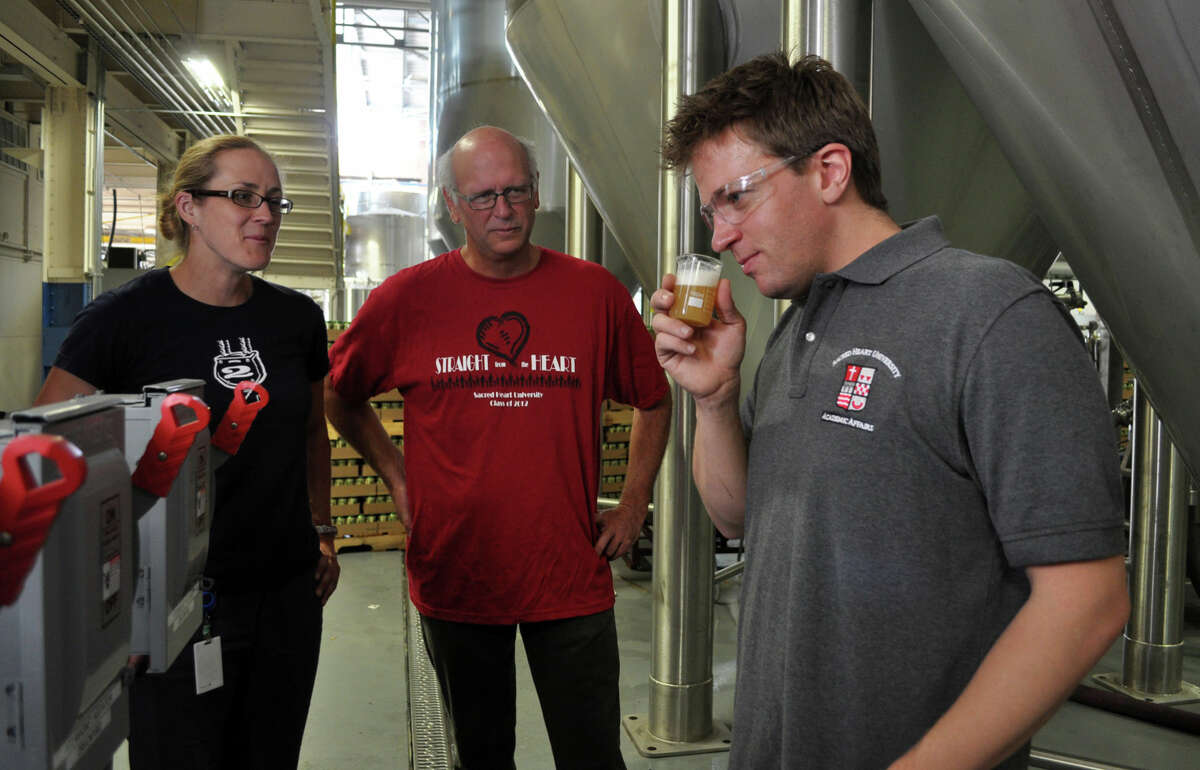 Sacred Heart biology professors Geffrey Stopper (right) and  Kirk Bartholomew at Two Roads Brewing Co. with Kendra Frederick, former director of quality assurance at the brewery. (August 2013)