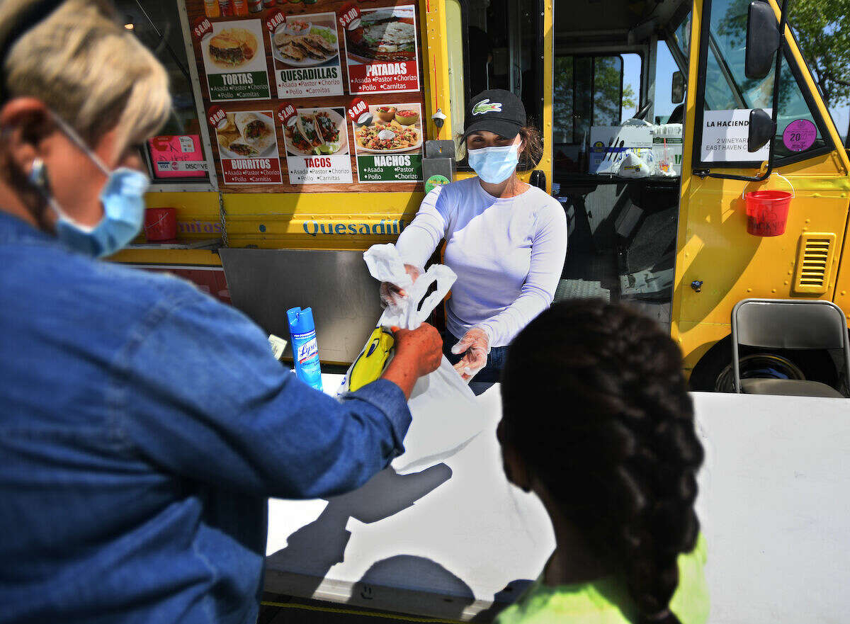 Andrea Figueroa, of West Haven, waits on customers at the Tacos los michoacanos food truck at Long Wharf in New Haven, Conn. on Tuesday, May 26, 2020. The trucks were forced to close when the coronavirus pandemic hit to address health department concerns including the use of masks and social distancing.