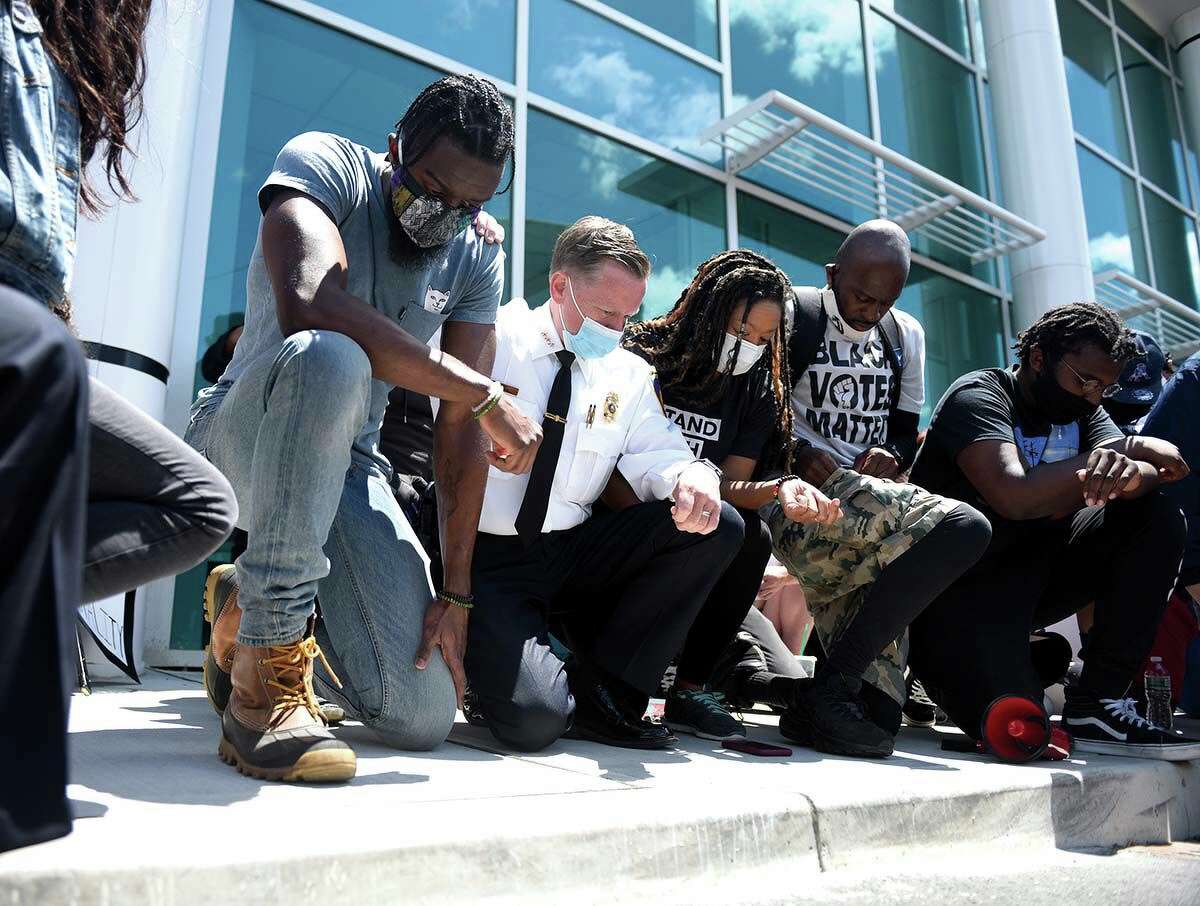 Stamford Police Chief Tim Shaw, second from left, takes a knee with #JusticeForBrunch Black Lives Matter protest organizers outside the Stamford Police Department in Stamford, Conn. Sunday, May 31, 2020. About 500 people marched from Harbor Point to the Stamford Police Station in honor of George Floyd and all other victims of police brutality. Protestors also shouted the name of Steven Barrier, who died in Stamford Police custody in October of 2019. Stamford Police Chief Tim Shaw spoke at the event saying "This police department is not silent. We are disgusted as well," before taking a knee with protestors for a moment of silence.