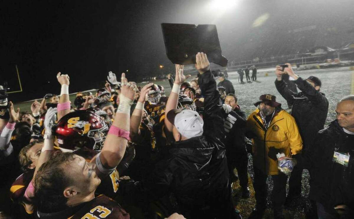 St. Joseph coach Joe Della Vecchia holds aloft last year’s Class L championship trophy. The three-time defending state champion Hogs will be playing in Class M for the second time in three seasons in 2020 — if football gets played as expected, this fall,