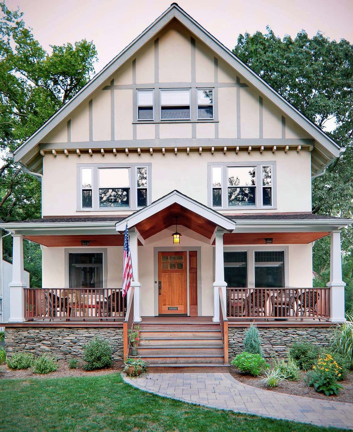This historic, Craftsman-style Colonial house was transformed with characteristic details: gabled roof, tapered square columns, wide stairs, warm natural materials and textures like a stained wood ceiling and porch platform clad in natural stone.